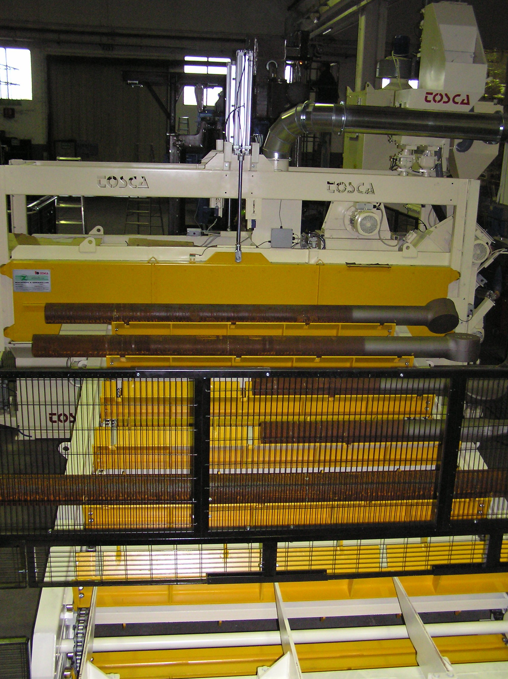 Tiges de vérin non grenaillées, posées sur une grenailleuse sur-mesure
