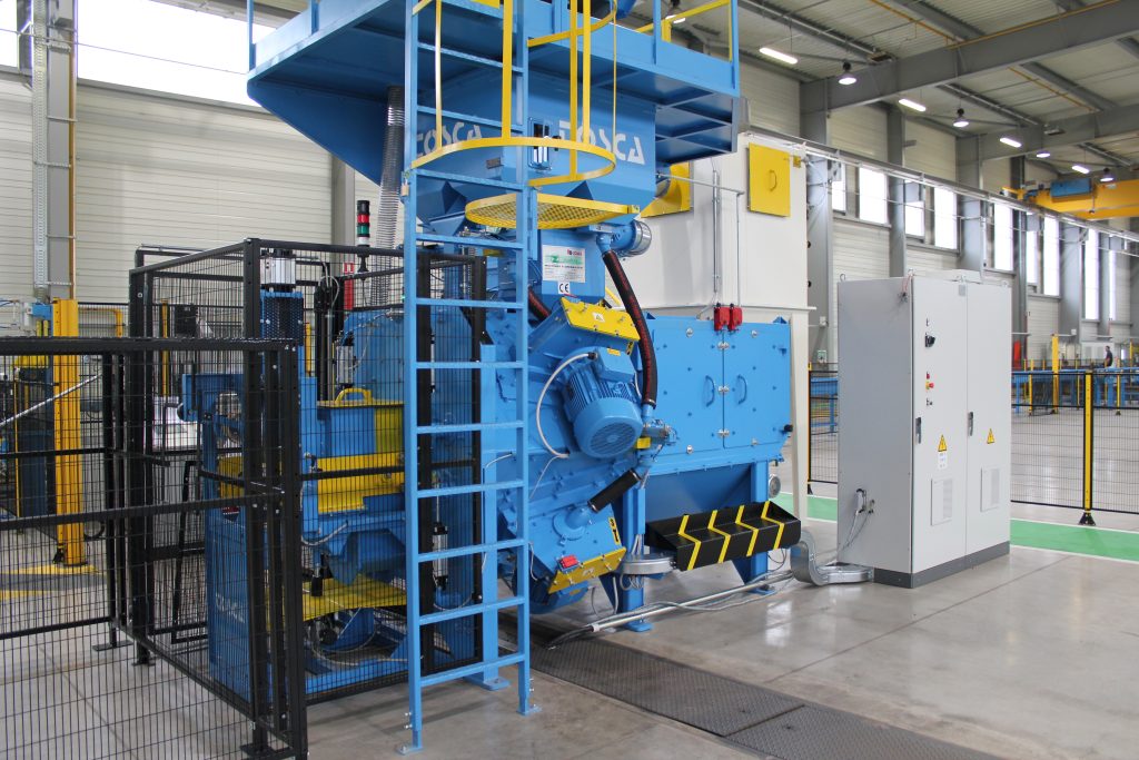 Grenailleuse industrielle TOSCA bleue et jaune avec plateforme, en usine