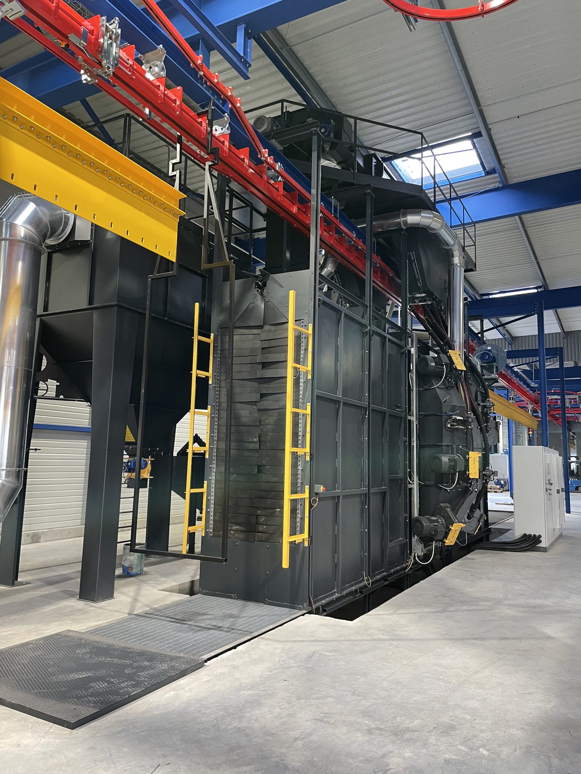 Grenailleuse à tunnel continu industrielle avec convoyeurs rouge et jaune dans atelier