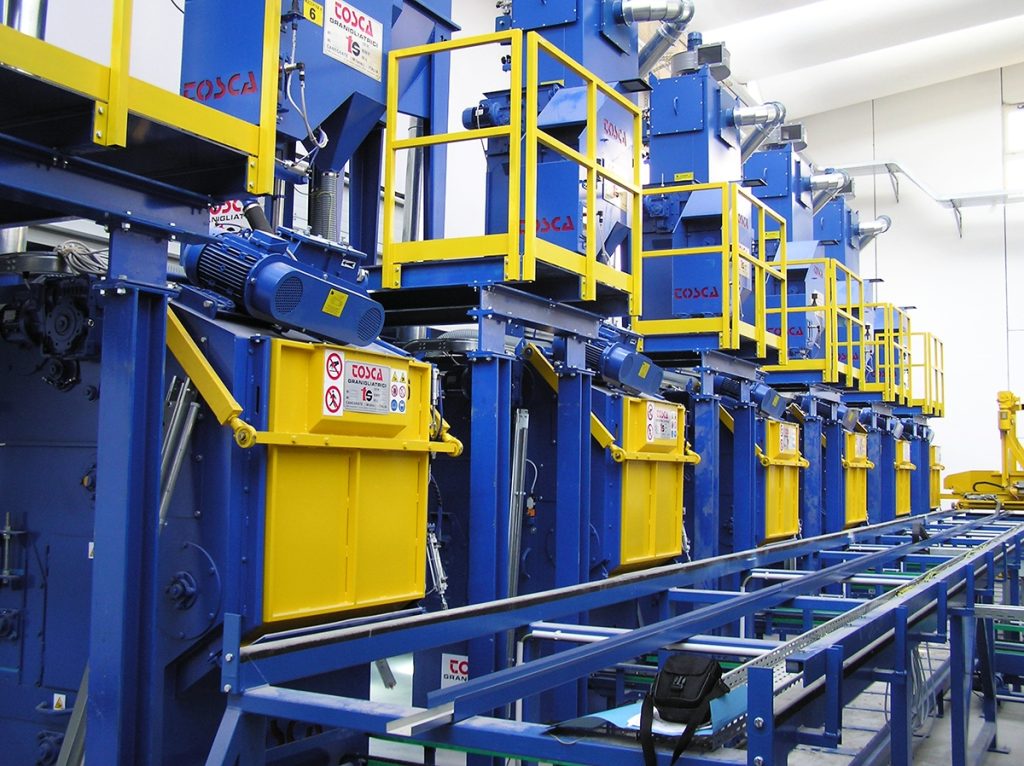 Rangée de grenailleuses TOSCA bleues et jaunes en ligne de production